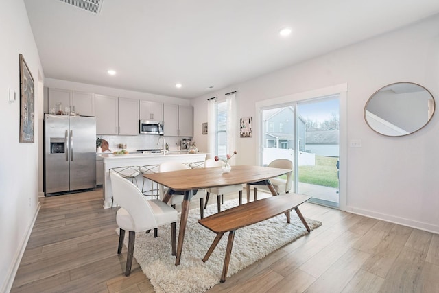 dining room featuring light wood-type flooring, visible vents, baseboards, and recessed lighting