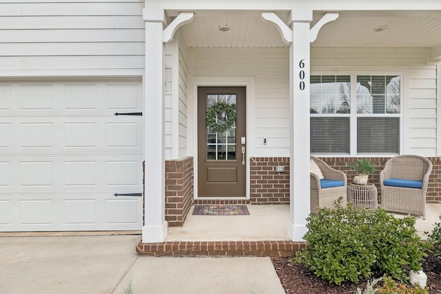 view of exterior entry with driveway, a porch, and brick siding