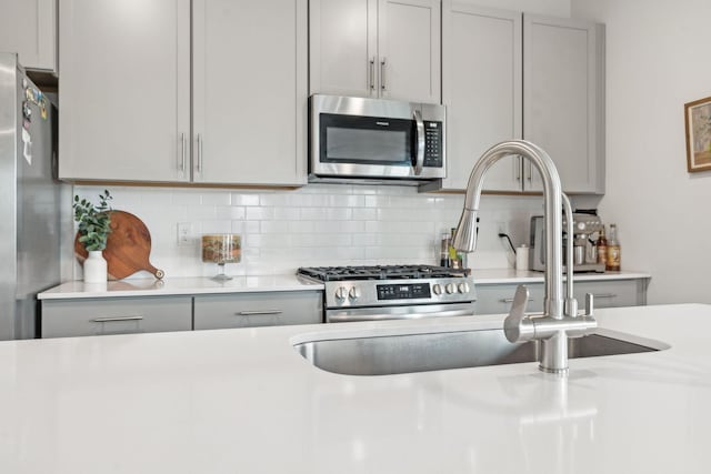 kitchen featuring gray cabinets, stainless steel appliances, and light countertops