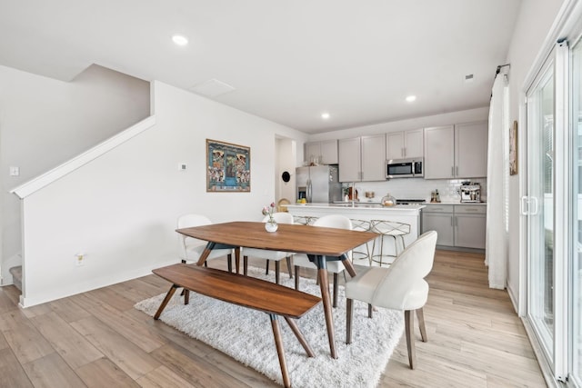 dining space featuring stairs, light wood-type flooring, baseboards, and recessed lighting