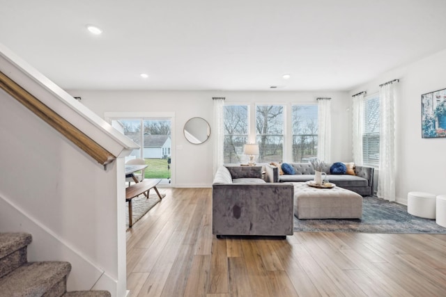 living area with light wood-type flooring, plenty of natural light, and stairs