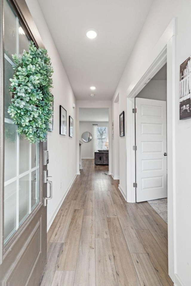 hallway featuring light wood-style flooring and baseboards