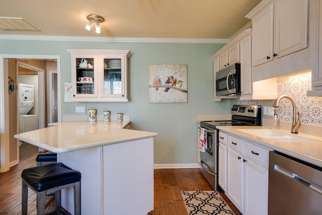 kitchen featuring ornamental molding, a sink, a kitchen breakfast bar, appliances with stainless steel finishes, and light countertops