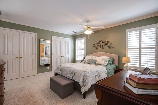 bedroom with crown molding, carpet, visible vents, and two closets