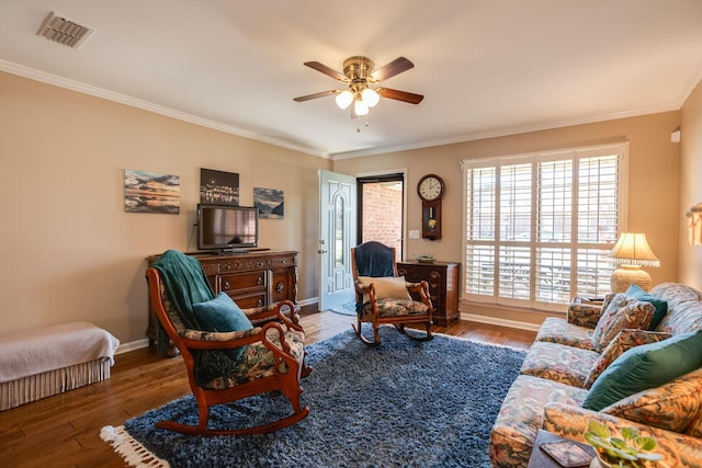 living area featuring wood finished floors, visible vents, and ornamental molding