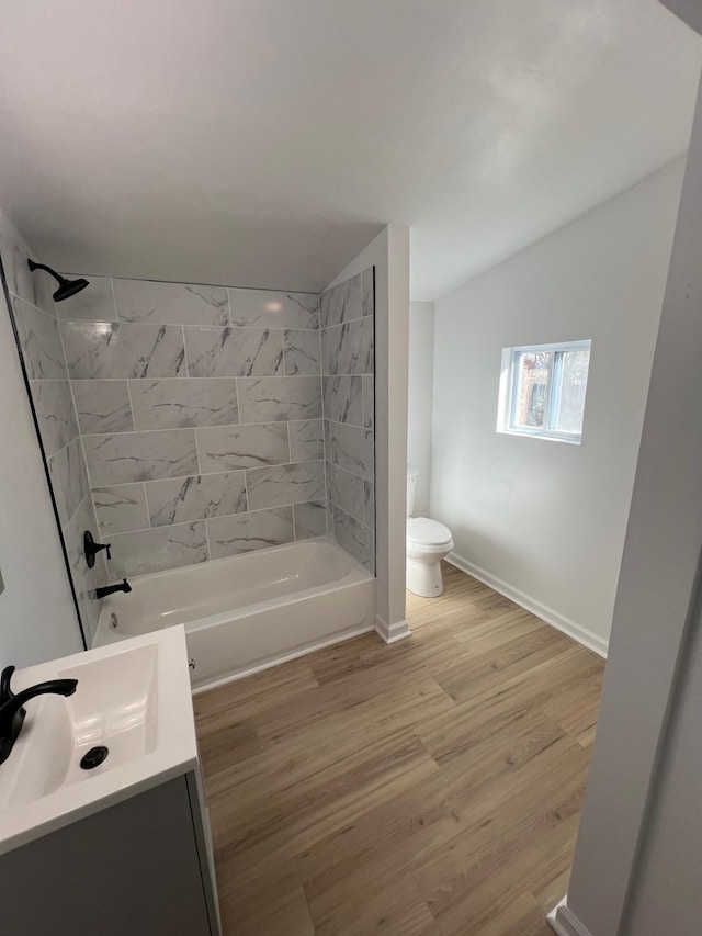 bathroom featuring toilet, wood finished floors, washtub / shower combination, baseboards, and vanity