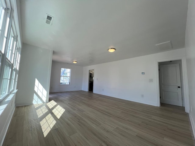 empty room featuring wood finished floors, visible vents, and baseboards