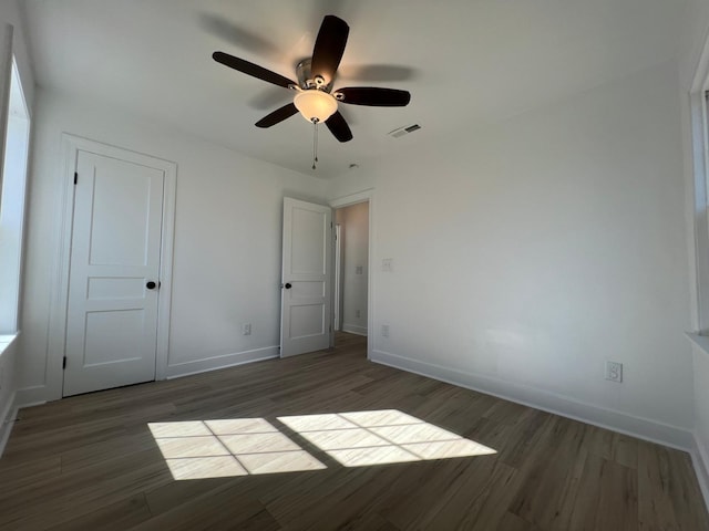 unfurnished bedroom featuring ceiling fan, visible vents, baseboards, and wood finished floors