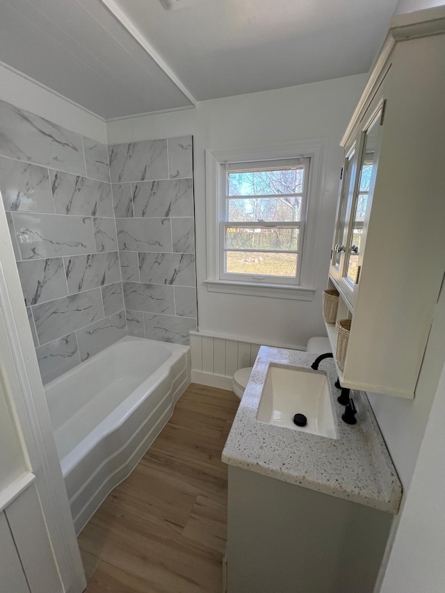 bathroom featuring vanity, washtub / shower combination, toilet, and wood finished floors