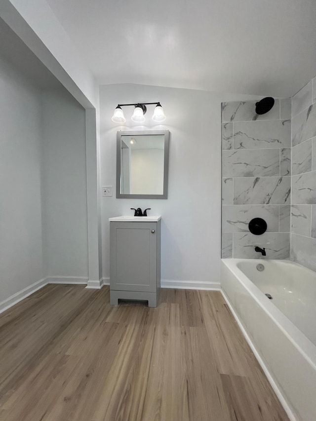 bathroom featuring washtub / shower combination, baseboards, wood finished floors, and vanity