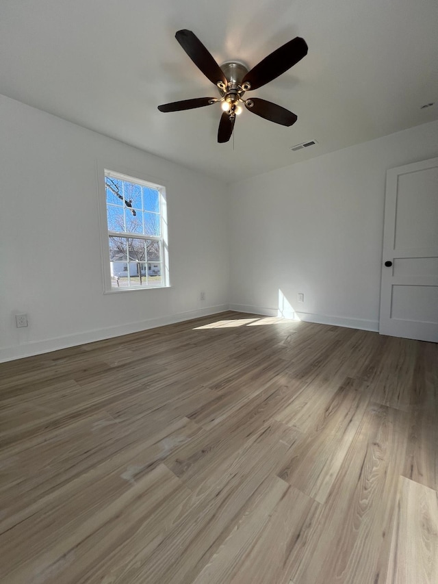 spare room featuring visible vents, baseboards, wood finished floors, and a ceiling fan