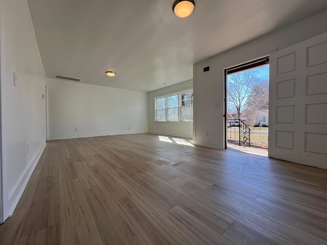 unfurnished living room with visible vents, baseboards, and wood finished floors