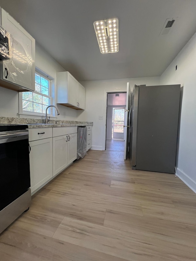 kitchen with stainless steel appliances, light wood finished floors, visible vents, and white cabinetry