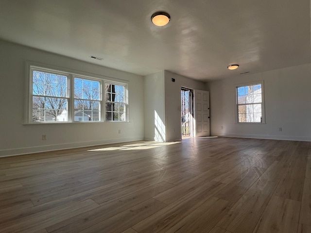 unfurnished living room featuring visible vents, baseboards, and wood finished floors