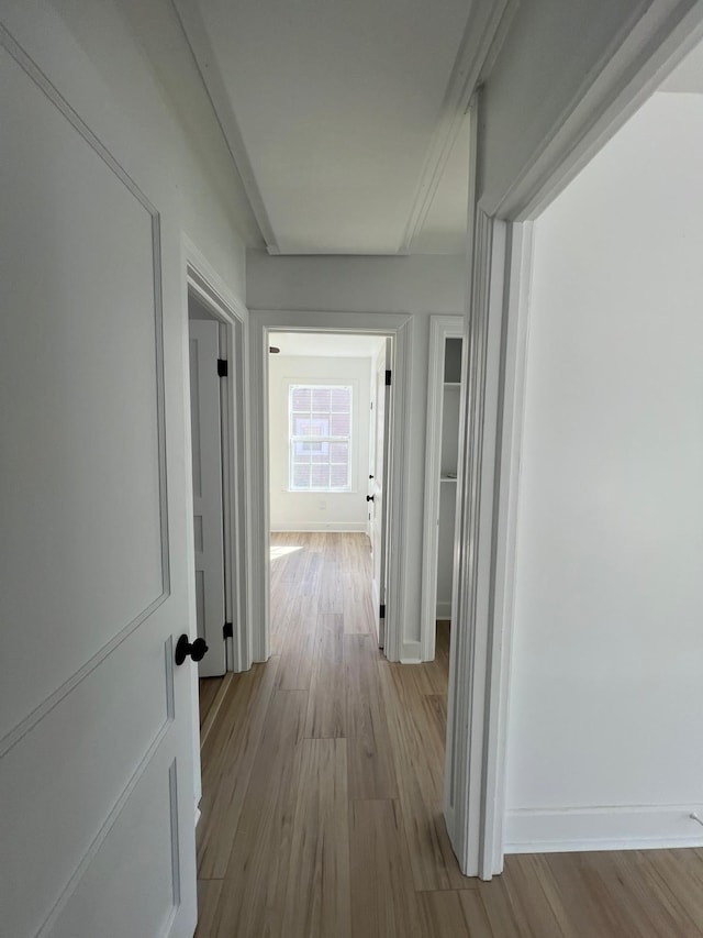 hallway featuring wood finished floors and baseboards