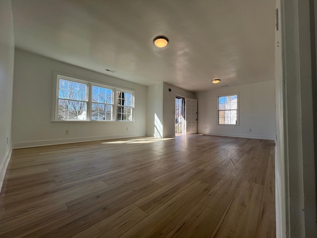 unfurnished living room with visible vents, baseboards, and wood finished floors