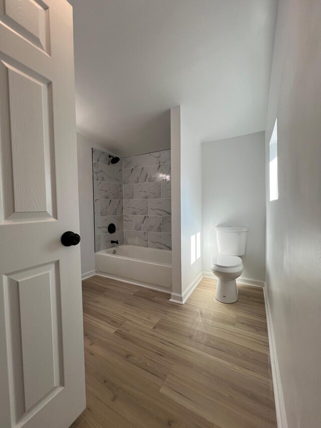 full bath with  shower combination, toilet, wood finished floors, and baseboards