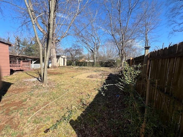 view of yard with a wooden deck, an outbuilding, a storage shed, and fence