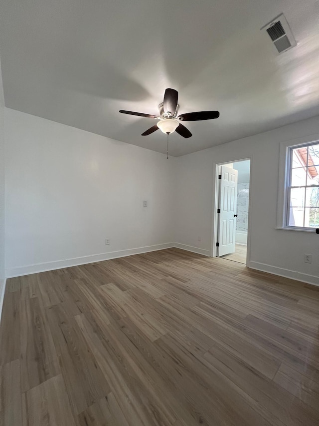 unfurnished room featuring ceiling fan, wood finished floors, visible vents, and baseboards