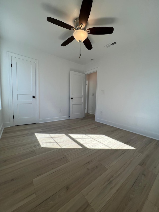 spare room with light wood-style floors, visible vents, and baseboards