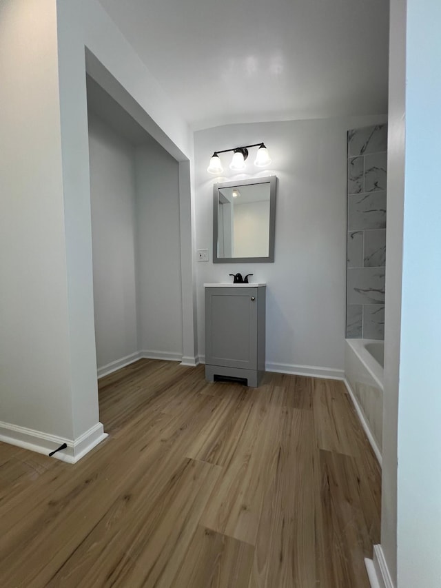 bathroom featuring baseboards, wood finished floors, and vanity