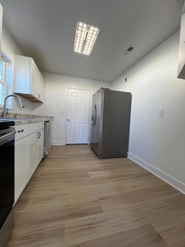 kitchen featuring visible vents, appliances with stainless steel finishes, white cabinetry, and a sink