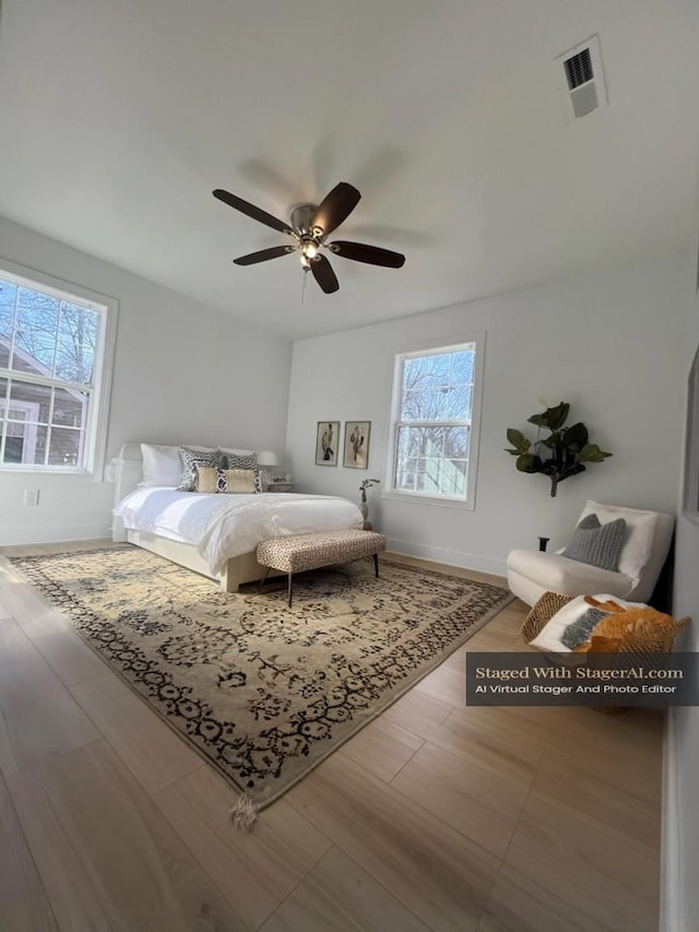 bedroom with visible vents, baseboards, wood finished floors, and a ceiling fan