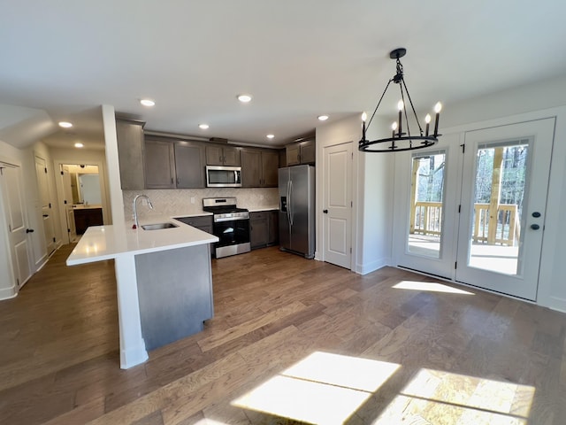 kitchen with wood finished floors, a sink, dark brown cabinets, appliances with stainless steel finishes, and backsplash