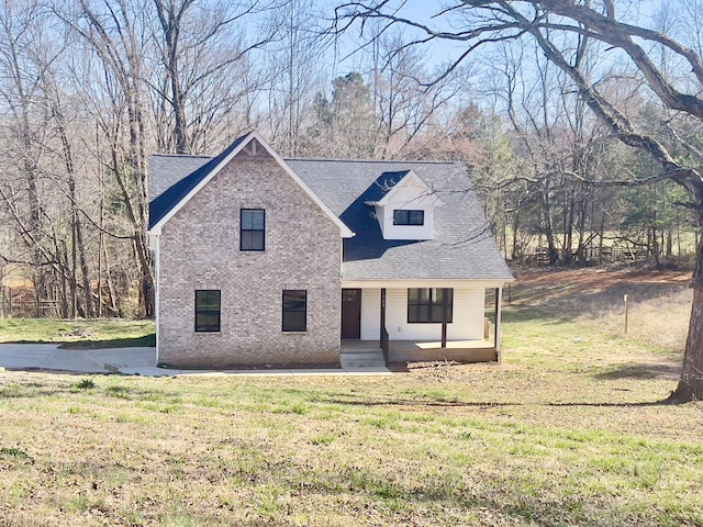 view of front of property featuring brick siding, covered porch, a front lawn, and roof with shingles