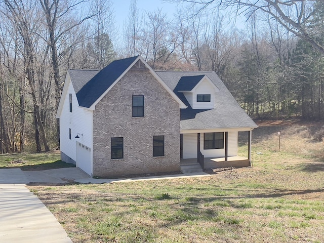 view of front of home featuring driveway, a porch, a front lawn, a garage, and brick siding