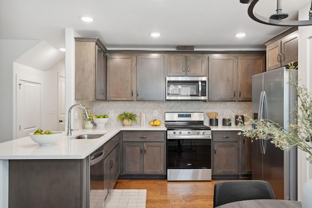 962 Belmont Rd, Clarksville, TN 37040 - kitchen with stainless steel appliances, a sink, a peninsula, light wood-style floors, and light countertops