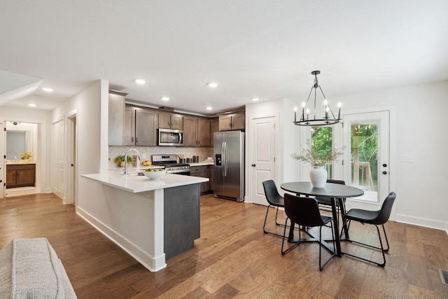 962 Belmont Rd, Clarksville, TN 37040 - kitchen with appliances with stainless steel finishes, light countertops, a chandelier, light wood-style flooring, and a peninsula