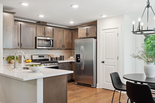 962 Belmont Rd, Clarksville, TN 37040 - kitchen with appliances with stainless steel finishes, light wood-style floors, backsplash, a peninsula, and a chandelier