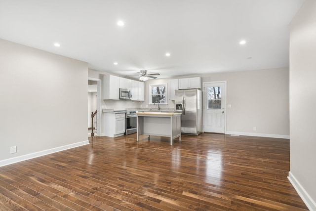 kitchen with stainless steel appliances, dark wood finished floors, light countertops, and baseboards