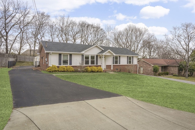 ranch-style house with a shingled roof, brick siding, fence, driveway, and a front lawn