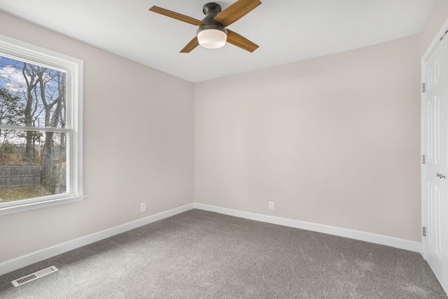 carpeted empty room with a ceiling fan, visible vents, and baseboards