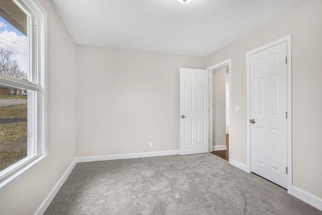 unfurnished bedroom with carpet floors, multiple windows, and baseboards