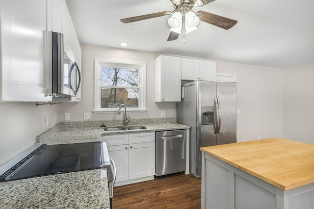 kitchen featuring dark wood-style flooring, wooden counters, appliances with stainless steel finishes, white cabinets, and a sink