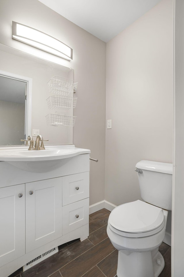 bathroom with toilet, wood finished floors, vanity, visible vents, and baseboards