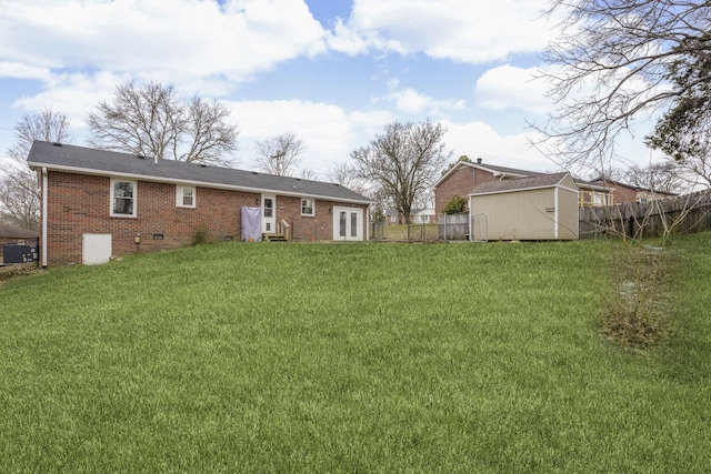 rear view of house featuring crawl space, brick siding, a lawn, and fence