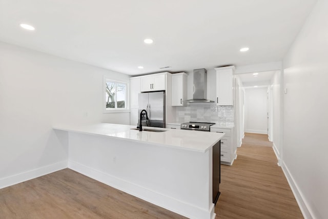 kitchen featuring a sink, decorative backsplash, light countertops, stainless steel appliances, and wall chimney exhaust hood