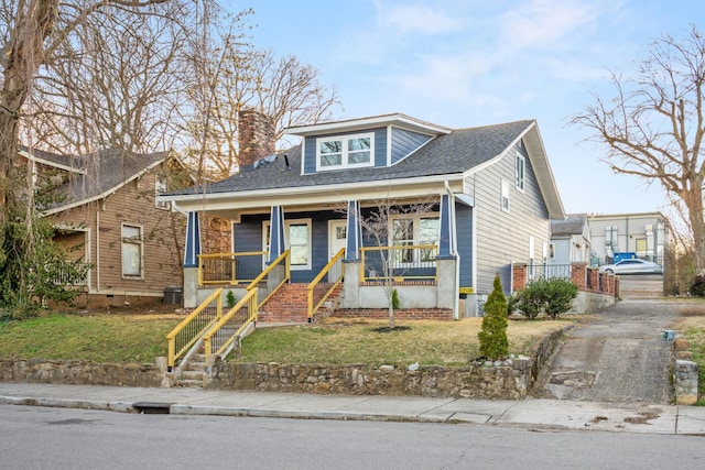 bungalow-style home featuring a porch, a chimney, a front lawn, and a shingled roof