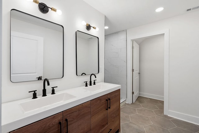 full bath featuring double vanity, baseboards, visible vents, and a sink