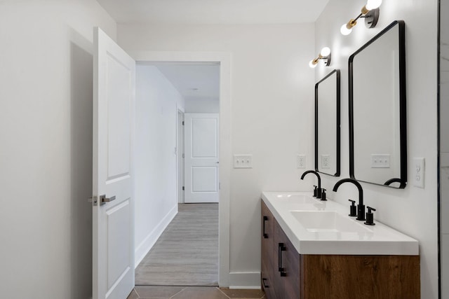 bathroom featuring double vanity, baseboards, and a sink