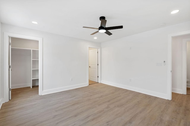 unfurnished bedroom featuring light wood-style flooring, a spacious closet, and recessed lighting