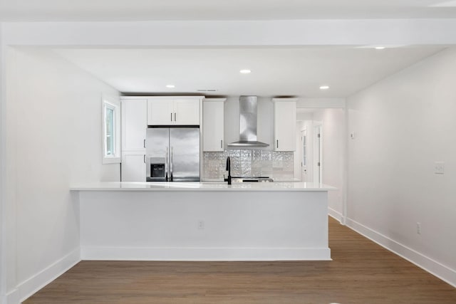 kitchen featuring decorative backsplash, stainless steel fridge, wall chimney exhaust hood, and dark wood-style flooring