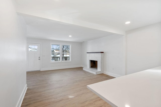 unfurnished living room with recessed lighting, baseboards, a fireplace, and light wood finished floors