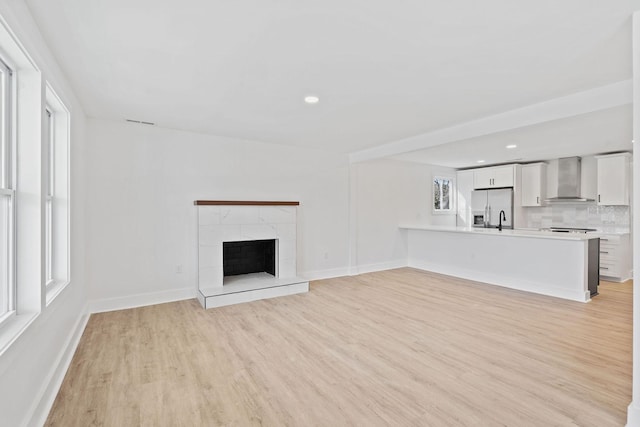 unfurnished living room with recessed lighting, light wood-style flooring, a fireplace, and baseboards