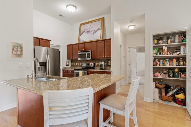 kitchen featuring visible vents, backsplash, appliances with stainless steel finishes, a sink, and a kitchen breakfast bar