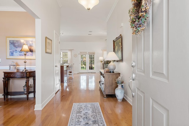 foyer with light wood finished floors, baseboards, and ornamental molding